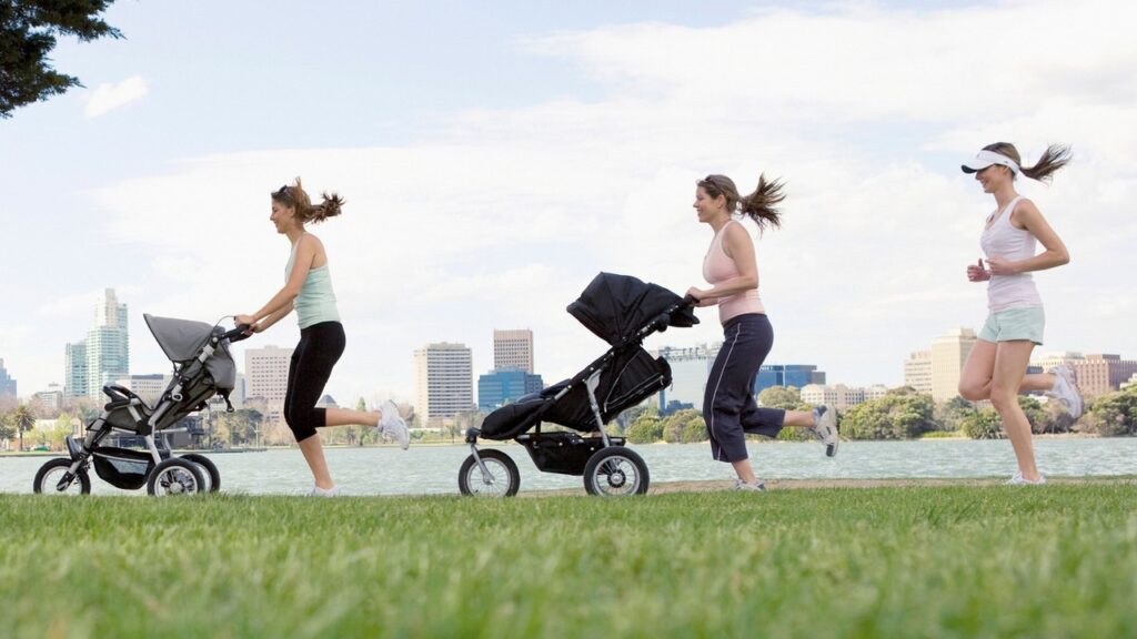 Women running while pushing strollers with city skyline in background