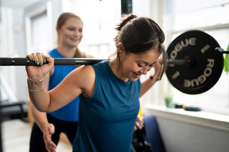 Vera helping a patient lift weights